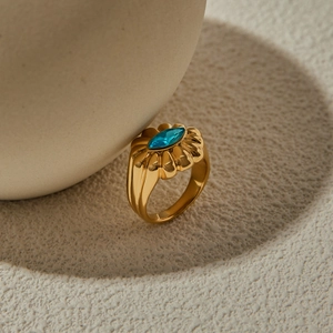 Macro shot of gold stainless steel ring with marquise blue zircon on sand background