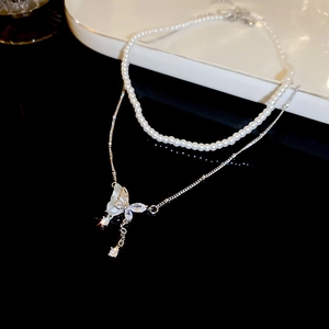 Macro detail of Y2K double layer necklace with pearl chain and zircon butterfly pendant