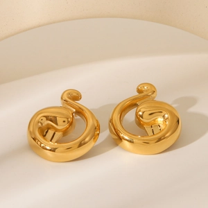 Macro view of golden spiral geometric earrings on minimalist beige architectural background
