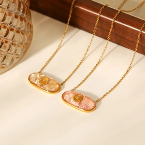 Macro shot of oval necklaces with pink shell resin pendants and gold sea shell accents