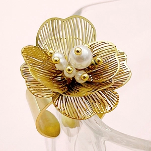 Detail of a hollow gold flower ring featuring elegant pearls and intricate wire petals