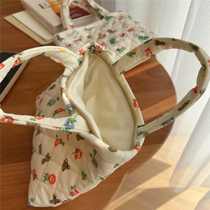Close-up of quilted floral bear pouch showing beige lining and durable metal zipper