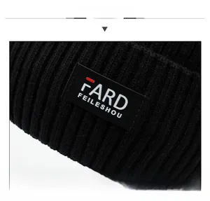 Close-up of thick ribbed knit texture and black logo patch on winter beanie hat