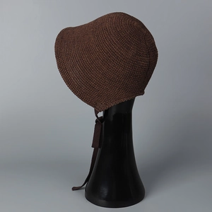 Detail of dark brown crochet knit bonnet with woven tie straps on a display stand
