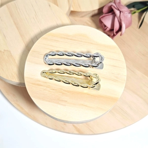 Detail of gold and silver twisted chain hair clips on elegant wooden display stands