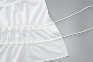 Detail of white beachwear set featuring intricate ruched fabric and slim drawstring ties