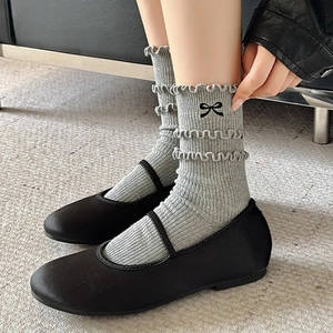Detail of grey ruffled crew socks with embroidered black bow and Mary Jane shoes