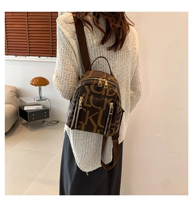 Detailed view of brown PU leather backpack with letter patterns and golden zippers
