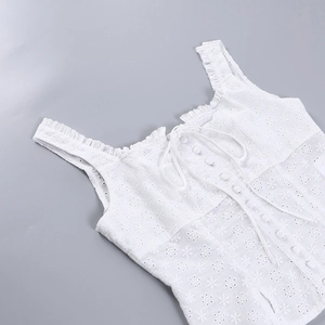 Détail du haut en dentelle blanche montrant la broderie florale et les boutons avant