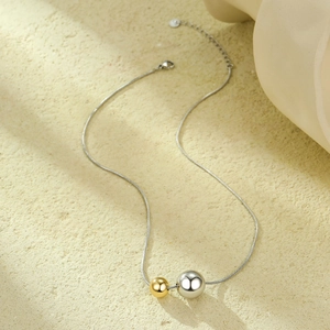 Detail of adjustable chain and polished gold and silver hollow sphere pendants on a necklace