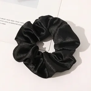 Close-up of a premium black silk scrunchie with elegant satin texture and elastic band