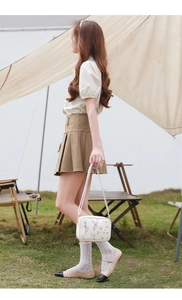Outdoor shot of white camera bag with delicate butterfly and floral embroidery detail
