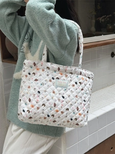 Close-up of quilted cotton tote bag featuring cute colorful puppy prints and a blue label