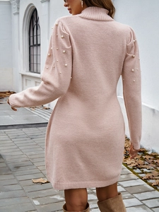 Détail d'une robe en tricot rose à col roulé avec des perles sur les manches vue de dos