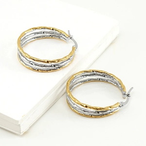 Two-tone twisted stainless steel hoop earrings in gold and silver finish on white background