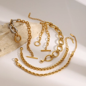 Golden stainless steel Cuban chain necklace and bracelet set on natural stone with soft shadows