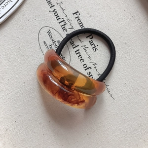 Close-up of amber marble texture acrylic resin ring on elastic hair tie hairband