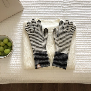 Primer plano de guantes de punto a rayas sobre un acogedor suéter de invierno texturizado