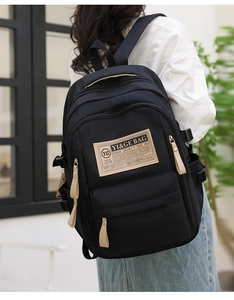 Black large capacity student backpack with brown leather pulls shown in use by a model