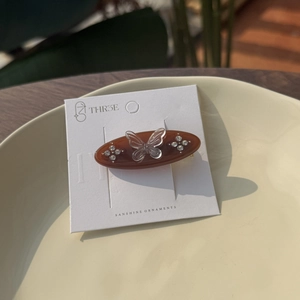 Elegant brown acetate butterfly hair clip with sparkling rhinestones on display card