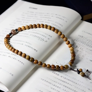 Macro view of Green Sandalwood beads with lotus pendant on an open vintage book