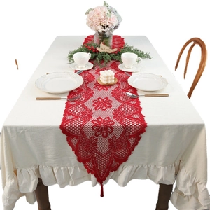 Red Christmas lace table runner with floral patterns and tassels on a festive dining table
