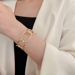 Close-up of chunky gold-tone link bracelet on wrist paired with a white blazer