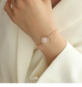 Close-up of a daisy pendant bracelet in 18K gold-plated steel on a woman's wrist