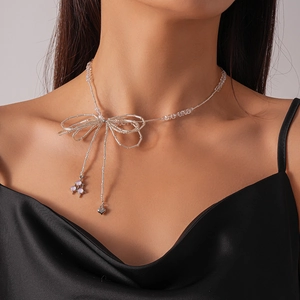 Close-up of a glass beaded bow necklace with a heart pendant on a model's neck