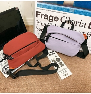 Detail of red and purple nylon crossbody bags with adjustable straps and woven label