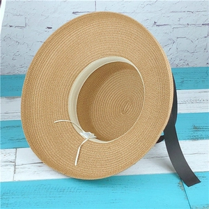 Detail view of woven straw hat interior with adjustable strap and black ribbon bow