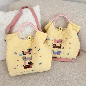 Detailed view of yellow quilted tote bag with cute cartoon embroidery and pink straps
