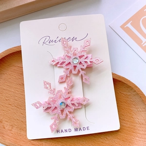 Pair of pink glittery snowflake hair clips with rhinestones on a display card