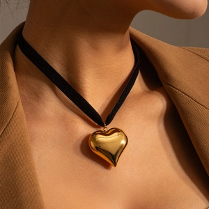 18k gold heart pendant on black velvet choker necklace worn with a brown blazer