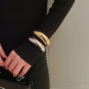 Close-up of polished gold and silver thick round bangles on a model wrist