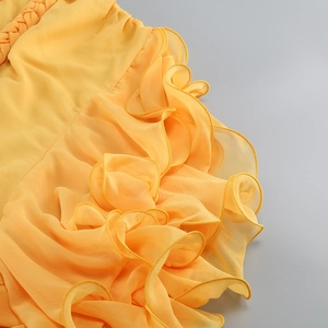 Détail de la texture à volants et du plissage artisanal sur une robe d'été jaune vif