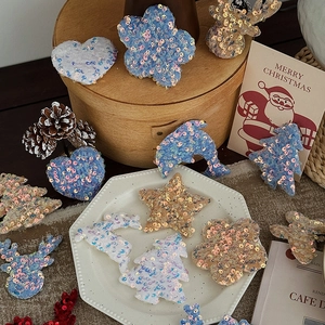 Assorted sequined Christmas fabric ornaments in heart and star shapes on a festive table