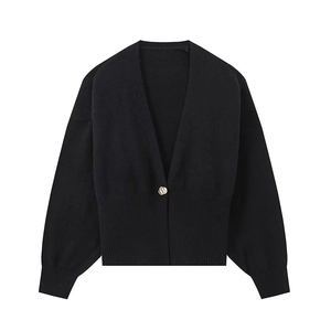Detailed view of black knit cardigan featuring a round golden button and V-neckline