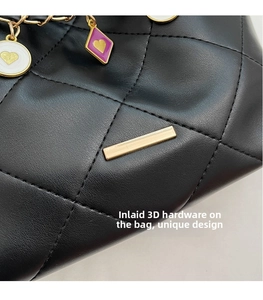 Close-up of black quilted leather with gold hardware and colorful heart charms