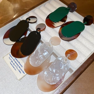 Détail de grandes boucles d'oreilles géométriques en acrylique avec motifs écailles rétro