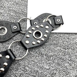 Macro detail of Y2K vintage black leather belt with silver rivets and metal ring link