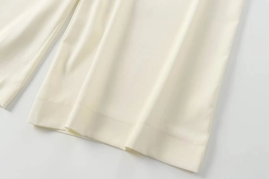Gros plan détaillé montrant la texture du tissu et l'ourlet de ce pantalon large blanc