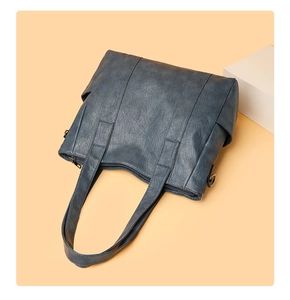 Macro view of blue-grey PU leather tote bag showing vintage texture and metal zipper