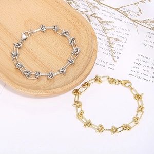 Industrial knot link chain bracelet in silver and gold finishes on a wooden display