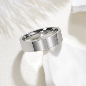 Polished silver stainless steel ring resting on a white minimalist stone display