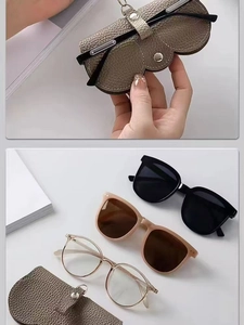 Détail d'étui à lunettes en cuir grainé gris avec bouton-pression et lunettes de soleil