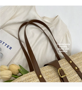 Detailed close-up of straw tote bag with brown leather handles and golden metal buckle