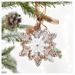 Macro shot of snowflake Christmas ornament with frosted texture hanging on snowy pine branch