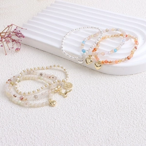 Detailed close-up of colorful freshwater pearl bracelets with heart and letter charms
