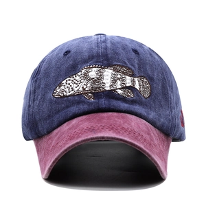 Close-up of fish embroidery on navy blue and burgundy washed cotton baseball cap